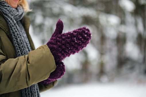 A side view of an unrecognizable Caucasian female using her mittens during cold winter days.