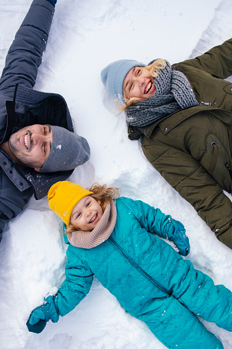 A from above view of a smiling Caucasian family having fun on the snow.