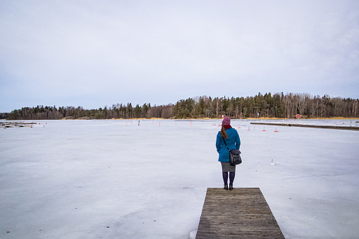 Full length of woman standing at frozen lake against sky