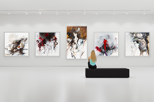 In an art center, young visitor looks at the artist's modern art collection. Modern colorful paintings on exhibition.