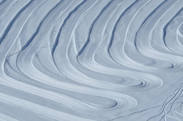 Close up of groomed tracks on a slope in a downhill ski resort on a sunny day. Shallow depth of field.