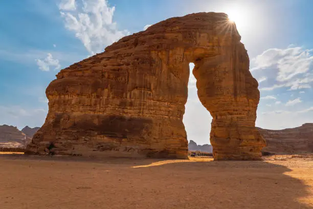 Jabal AlFil - Elephant Rock in Al Ula desert landscape, bright sun creates sunrays behind