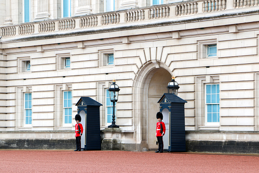 Two of the King and Queens Guards dressed in full uniform on duty outside Buckingham Palace, landmark building and tourist attraction in London, England, UK