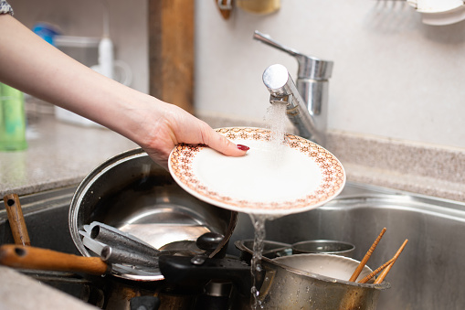 Woman's hands washing many dishes