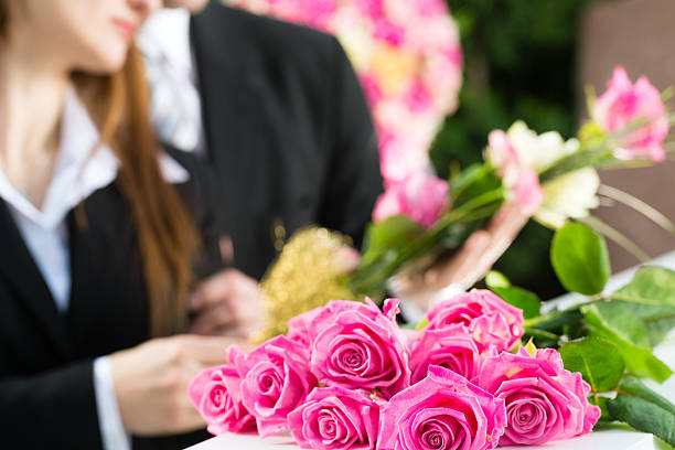 Mourning People at Funeral with coffin Mourning man and woman on funeral with pink rose standing at casket or coffin funeral parlor photos stock pictures, royalty-free photos & images