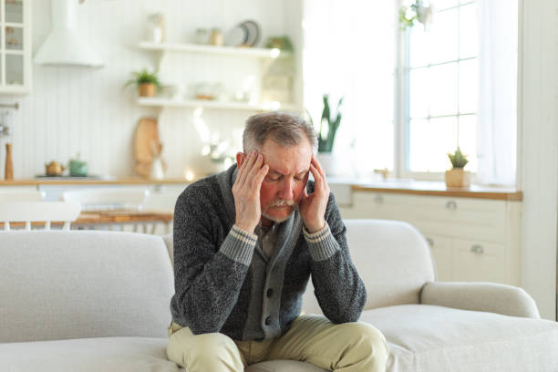 istock Headache pain. Unhappy middle aged senior man suffering from headache sick rubbing temples at home. Mature old senior grandfather touching temples experiencing stress. Man feeling pain hurt in head. 1859774501