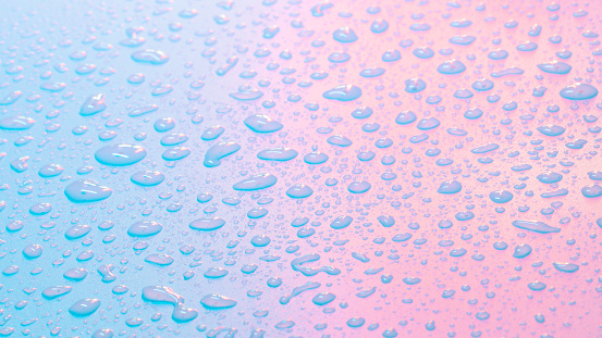 Water drops in neon lighting. Abstract unicorn colored background. Colorful texture backdrop.