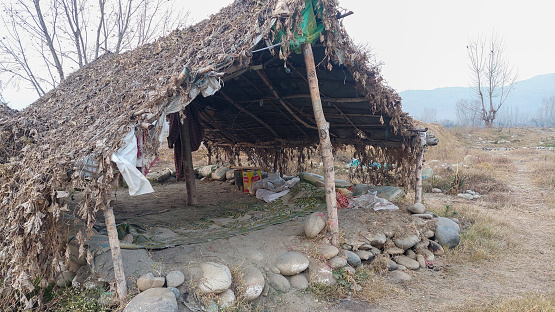 The entrance to the temporary straw hut, rural landscape, daylight and shade.
