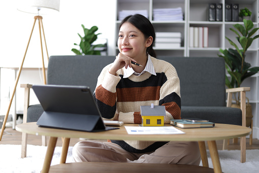 Young asian woman planning finances for down payment and home loan. Financial Planning and Accounting at Home