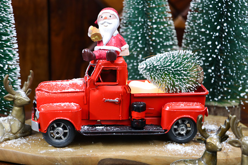 Stock photo showing a Christmas scene, which features Santa on a red truck with artificia, plastic spruce tree in the back.