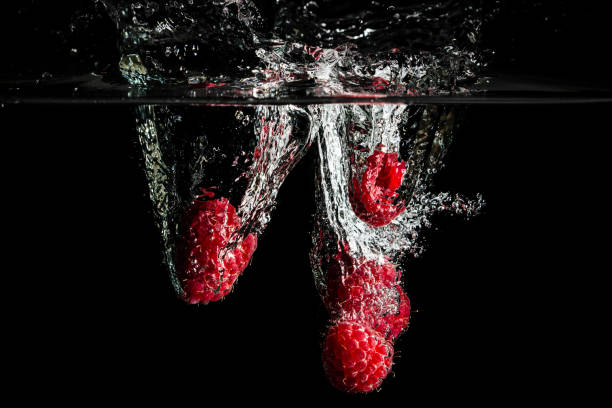 Raspberries splashing into water.