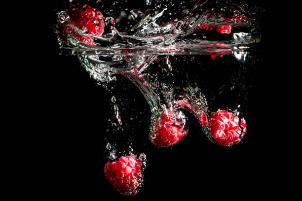 Raspberries splashing into water.
