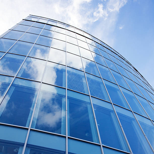 istock curved facade of modern glass blue office and clouds 185982735