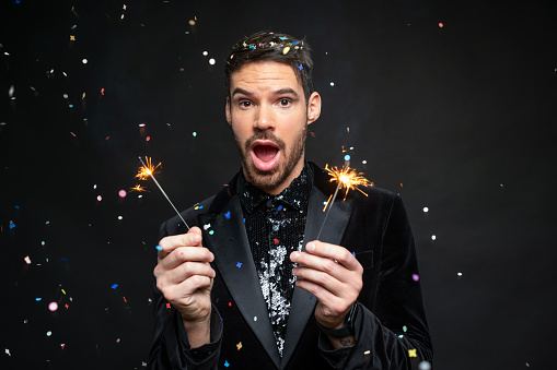 Man with sparklers on black background. Christmas party concept.
