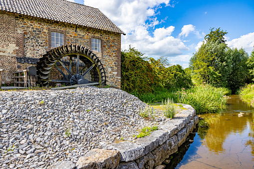 Geul river and old Eper or Wingbergermolen water mill, stone building with two windows, trees and wild vegetation in background, sunny day at Terpoorterweg, Epen, South Limburg, Netherlands