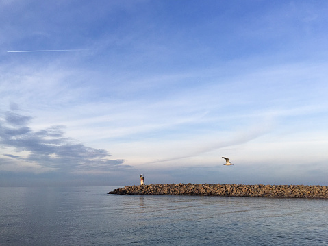 Old lighthouse at coastline with sea and sky background. Rocky coastline. Seascape