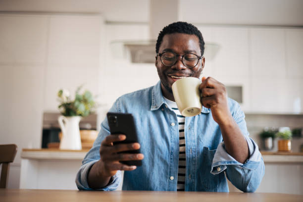 istock Shot of a young man with glasses using a smartphone and having coffee 1859906610