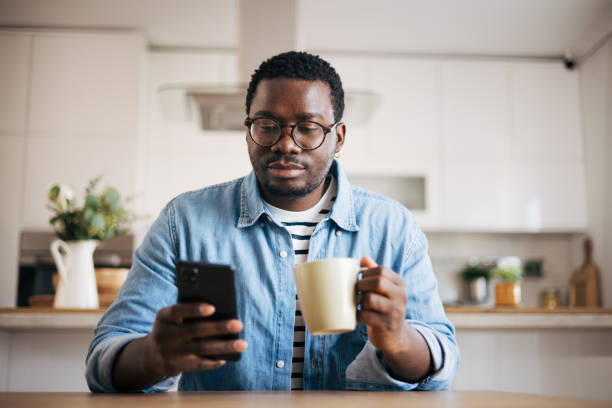 istock Shot of a young man with glasses using a smartphone and having coffee 1859907117