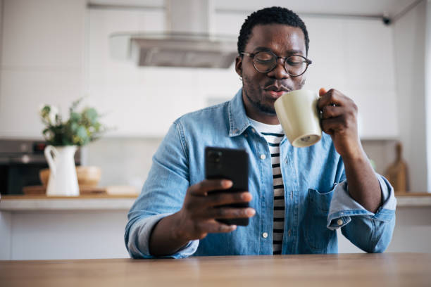 istock Shot of a young man with glasses using a smartphone and having coffee 1859907607