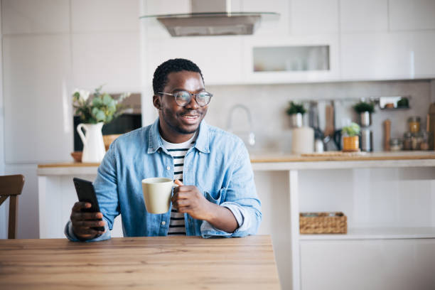 istock Shot of a young man with glasses using a smartphone and having coffee 1859908664