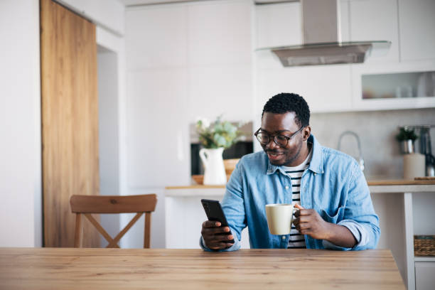 istock Shot of a young man with glasses using a smartphone and having coffee 1859908667