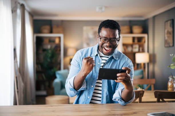 istock Black young man excited playing mobile game on his smartphone 1859928176