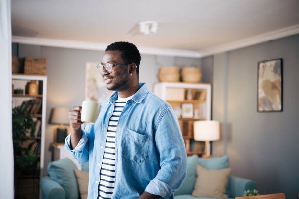 istock Side view of man drinking hot coffee and looking out a window 1859938656