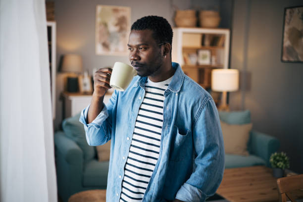 istock Side view of man drinking hot coffee an looking out a window 1859940826