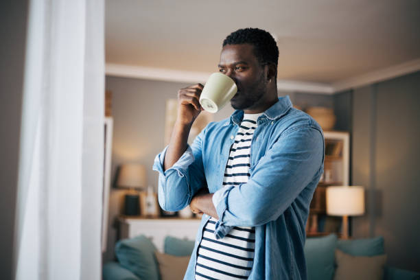 istock Side view of man drinking hot coffee and looking out a window 1859940827