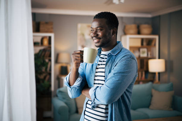 istock Side view of man drinking hot coffee and looking out a window 1859940839