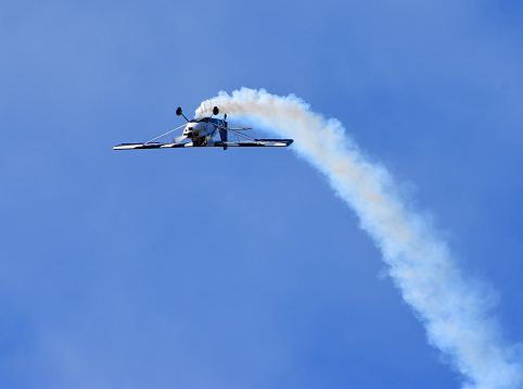 Little Gransden, Cambridgeshire, England - August 27, 2023: American Champion 8KCAB Decathlon aircraft stunt flying with smoke.