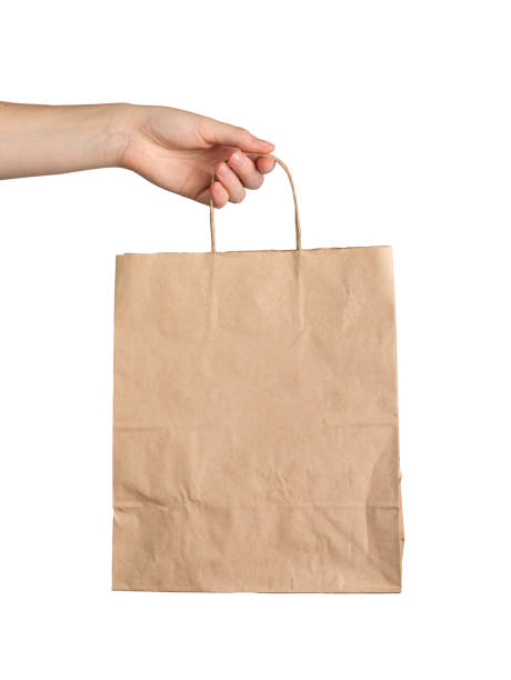 istock Hand holding paper bag, kraft brown packet mockup isolated on white background 1859957677