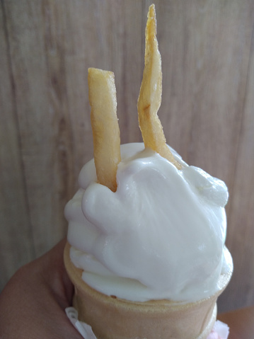 Penang, Malaysia 

A hand holding a sundae cone, and two fries stuck into the sundae, acting as antenna.
Brown background. Copy space available.