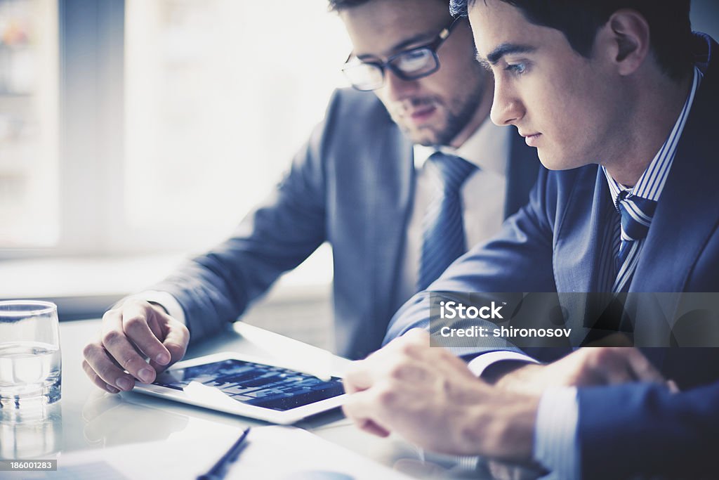 Working with touchpad Image of two young businessmen using touchpad Adult Stock Photo