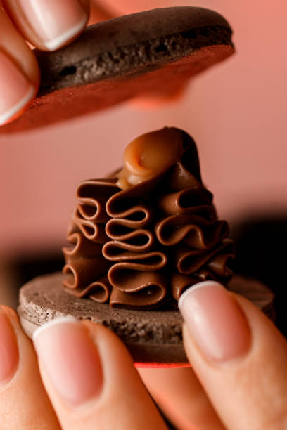 istock Female hands hold two pieces of macaroon close-up 1860032369