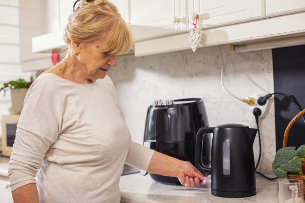 istock Senior woman using electric kettle to make tea 1860036108