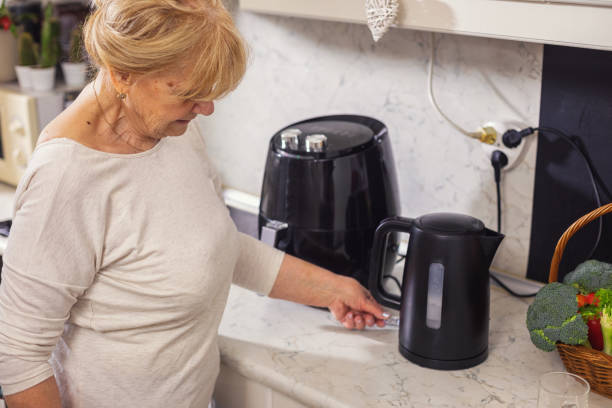 istock Senior woman using electric kettle to make tea 1860036120
