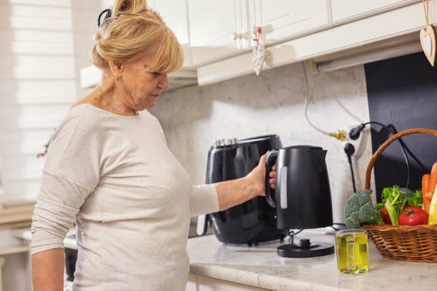 istock Senior woman using electric kettle to make tea 1860036669