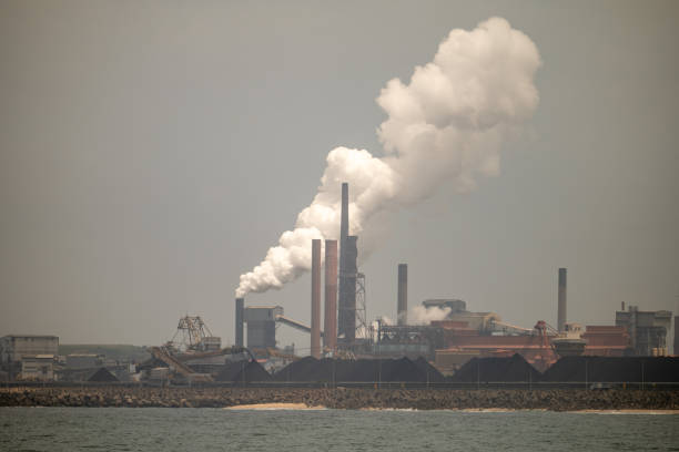 istock Industrial Factories Producing Pollution by the Ocean 1860055917
