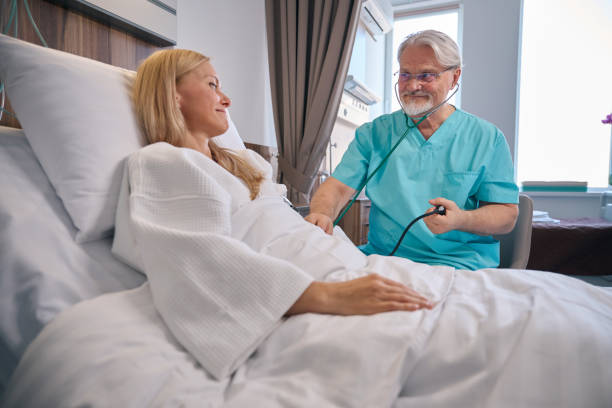 Doctor conducting physical examination of female patient during ward round stock photo