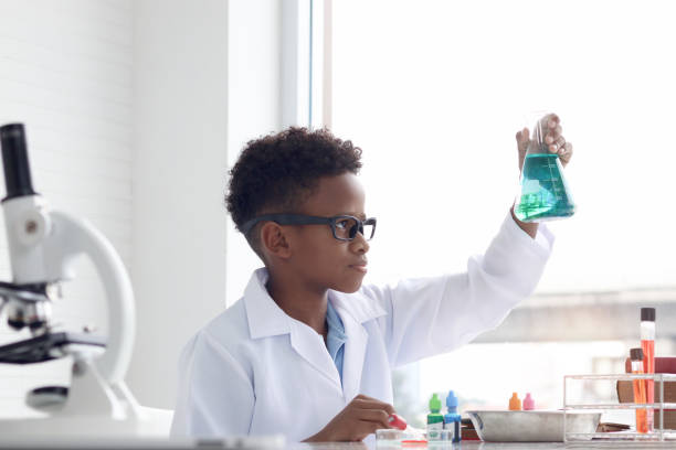 istock Concentrate African boy in lab coat holds chemical flask for doing science experiment, young schoolboy kid scientist having fun in chemistry laboratory class, little child doing research at school. 1860108662