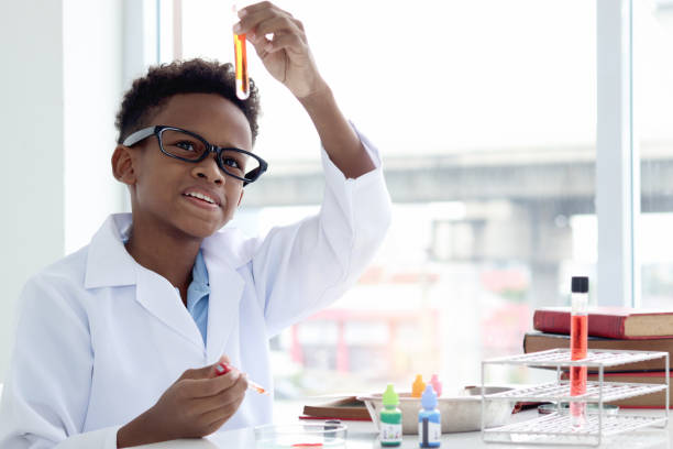 istock Happy smiling African boy in lab coat holding a test tube for doing science experiments, young schoolboy kid scientist having fun in chemistry laboratory class, little child doing research at school. 1860108663