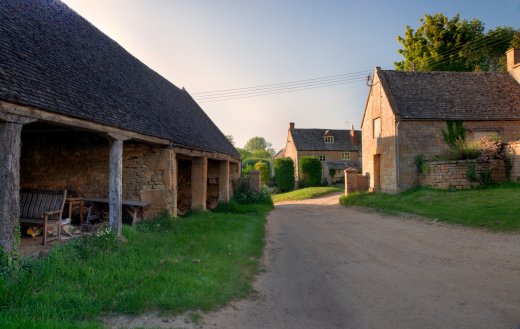 Old traditional English farm at sunset with cart shed and farmhouse.