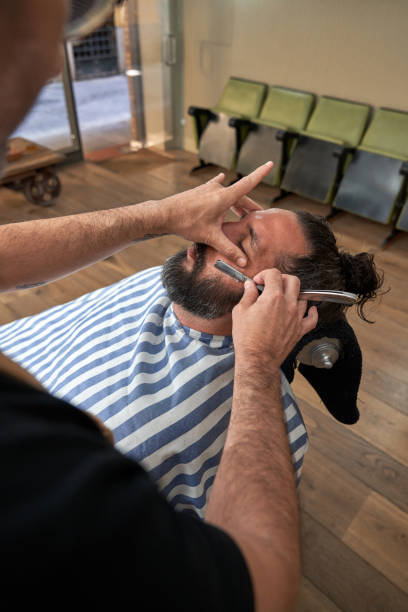 istock Unrecognizable barber trimming beard of client 1860142608