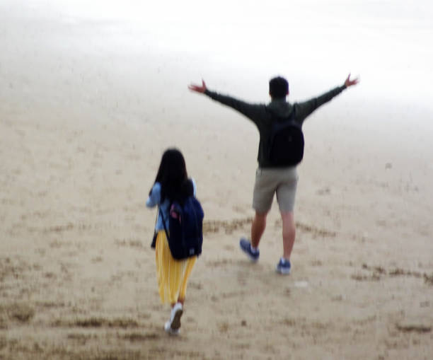 Scheveningen, the Netherlands - July 9 2019 A man and a woman walk on the beach. The man shows his delight by spreading his arms