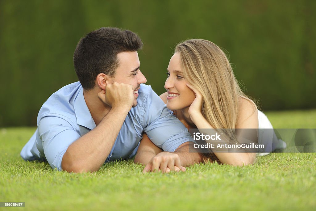 Couple in love dating and looking each other Couple in love dating and looking each other lying on the grass with a green background Adolescence Stock Photo