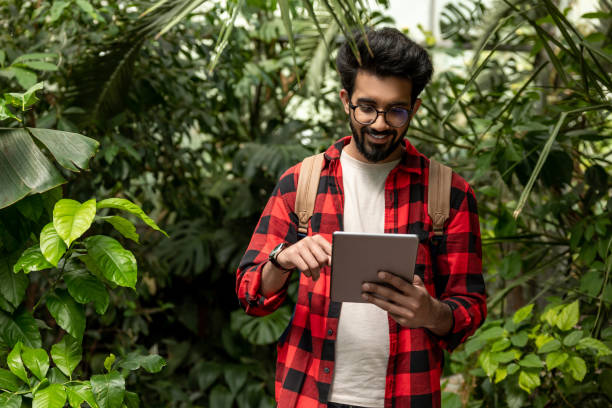 istock Hindu man with tablet in hands in botanical garden 1860190298
