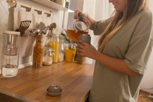 istock A woman pouring hot herbal tea from a kettle into reusable cup 1860227107