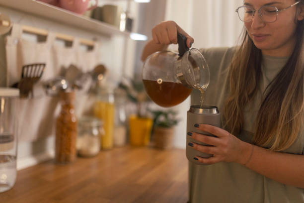 istock Beautiful woman pours herbal tea from a teapot into reusable cup 1860227109