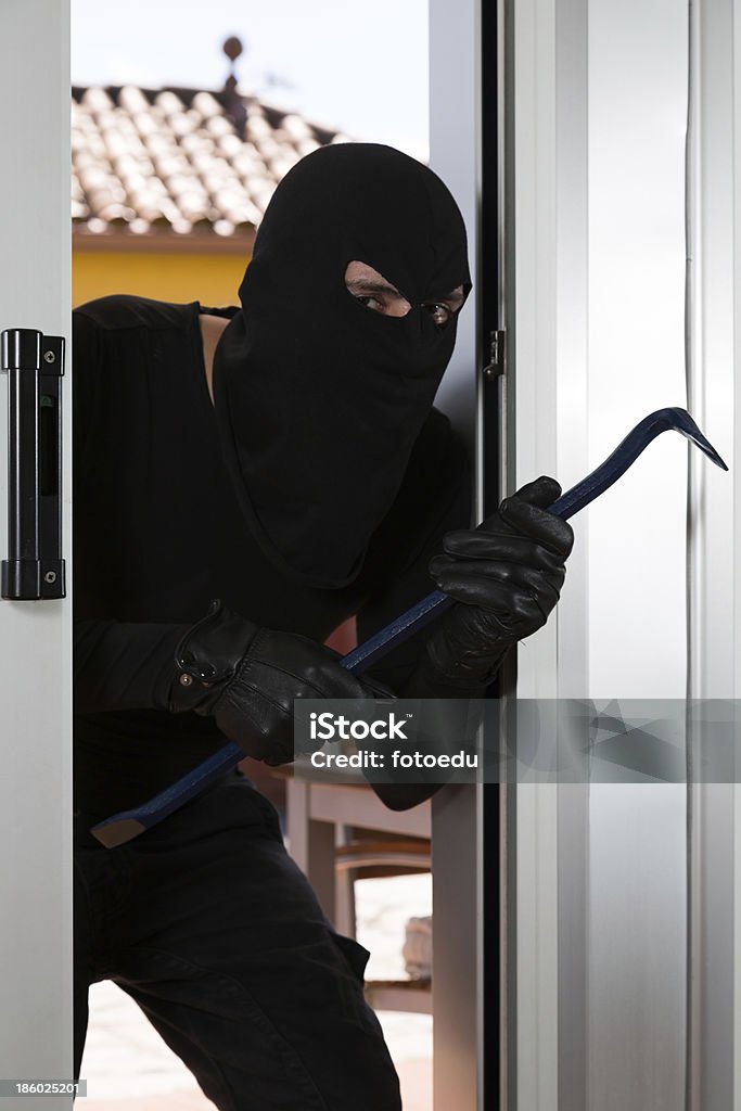 Thief with a bar of iron Thief with a bar of iron in the hand to open a door Adult Stock Photo